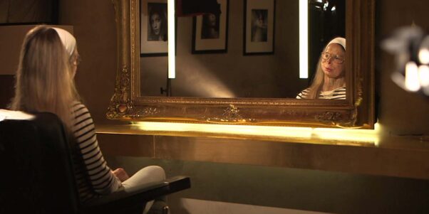 une femme au visage défiguré devant un miroir